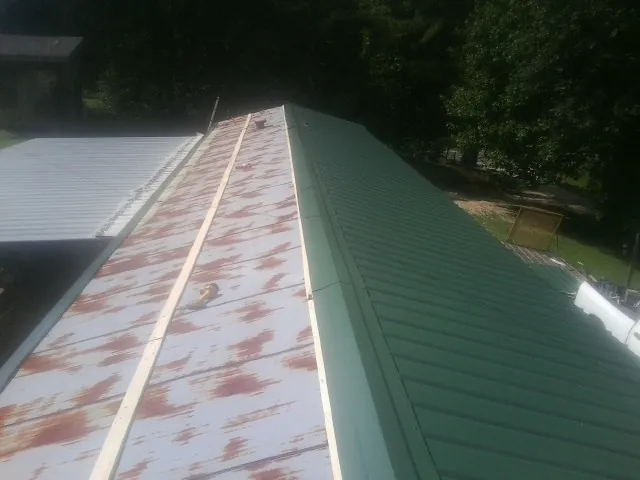 Old rusted panels beside newly installed green metal roofing — Wind Damage Roof Repair by Roofing Brothers in Murphy